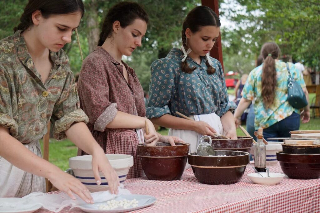 アメリカの地域料理 1 Pennsylvania Dutch women preparing traditional food at an outdoor community event.